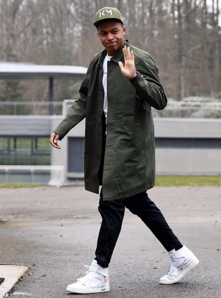 Kylian Mbappé wearing a khaki street style outfit with white off white sneakers