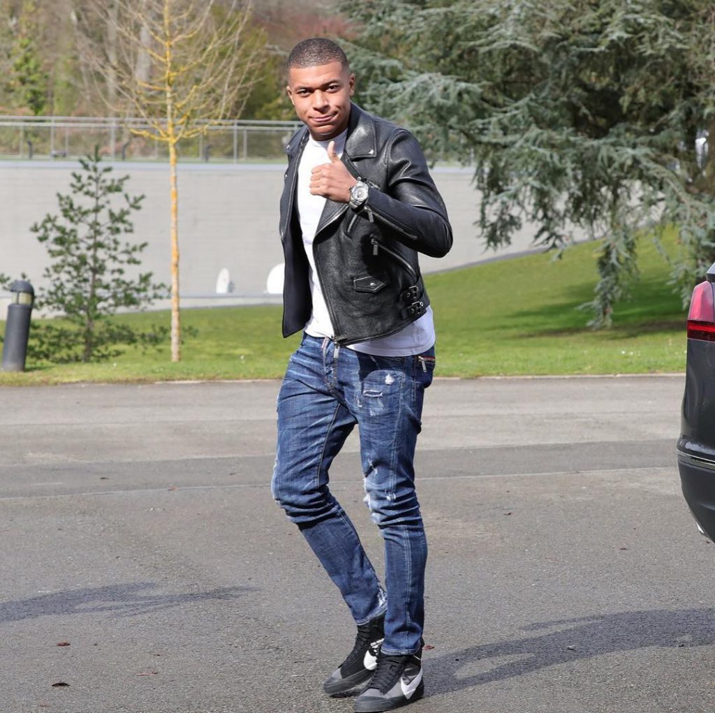 Kylian Mbappé wearing a black leather jacket and black off white sneakers